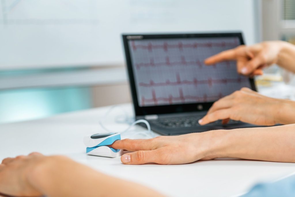 A close-up shot of a patient using a digital monitoring device with a screen showing the signals.