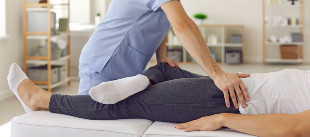 A doctor assists a male patient certain exercises while lying on the bed