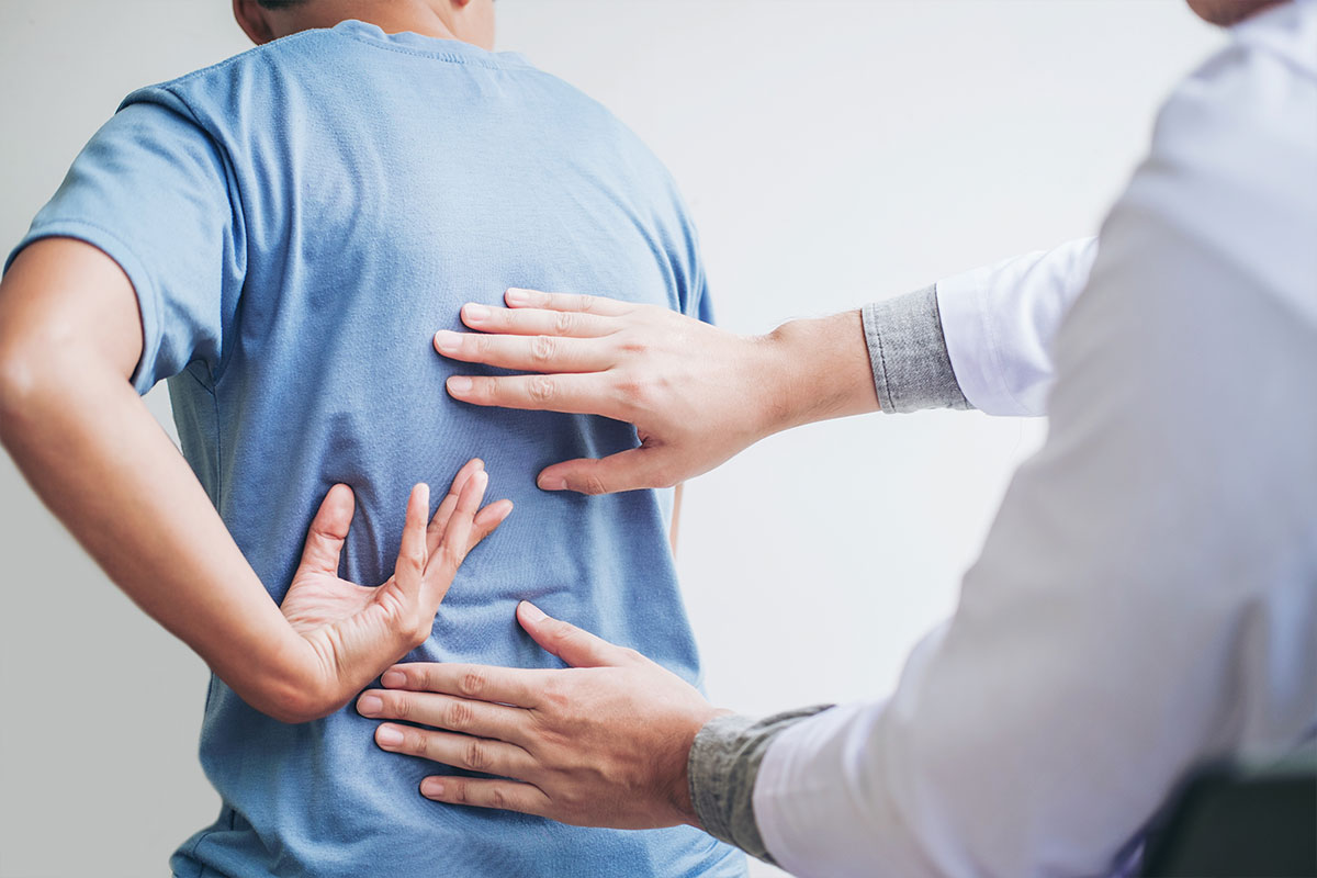 A medical expert checks a patient for low back pain.